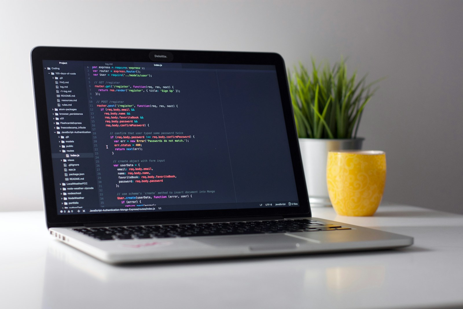Laptop showing code in an editor on a clean desk