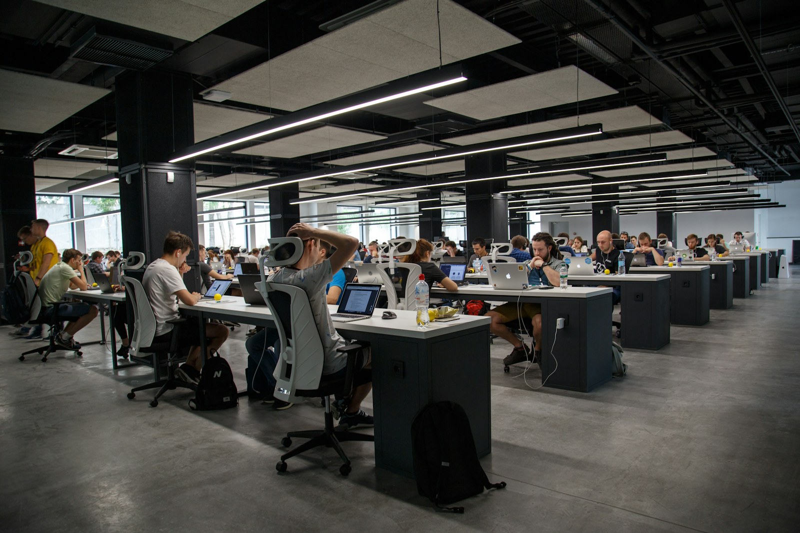 A large open-plan office of engineers working at long shared desks